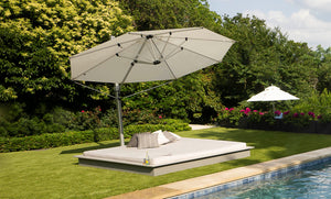 Ledge Lounger Echo Sunbed on a pool deck styled with pillows and a side table