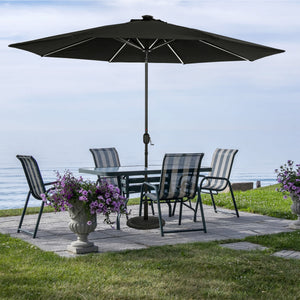Island Umbrella Calypso Fiesta Umbrella - black canopy with solar LED strips over a lakeside table