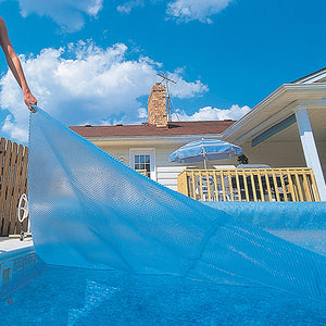 Blue Wave 12-mil Rectangular Solar Blanket - blanket being drawn across an in-ground pool by hand