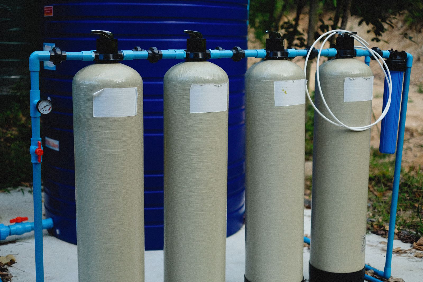 Row of filtration tanks with blue piping, similar to a pool filter on an equipment pad