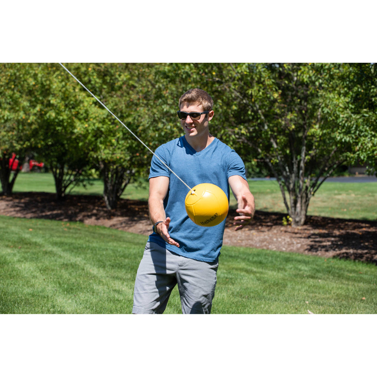 Hathaway Tetherball Set - player catching the yellow ball on its rope beside the pole