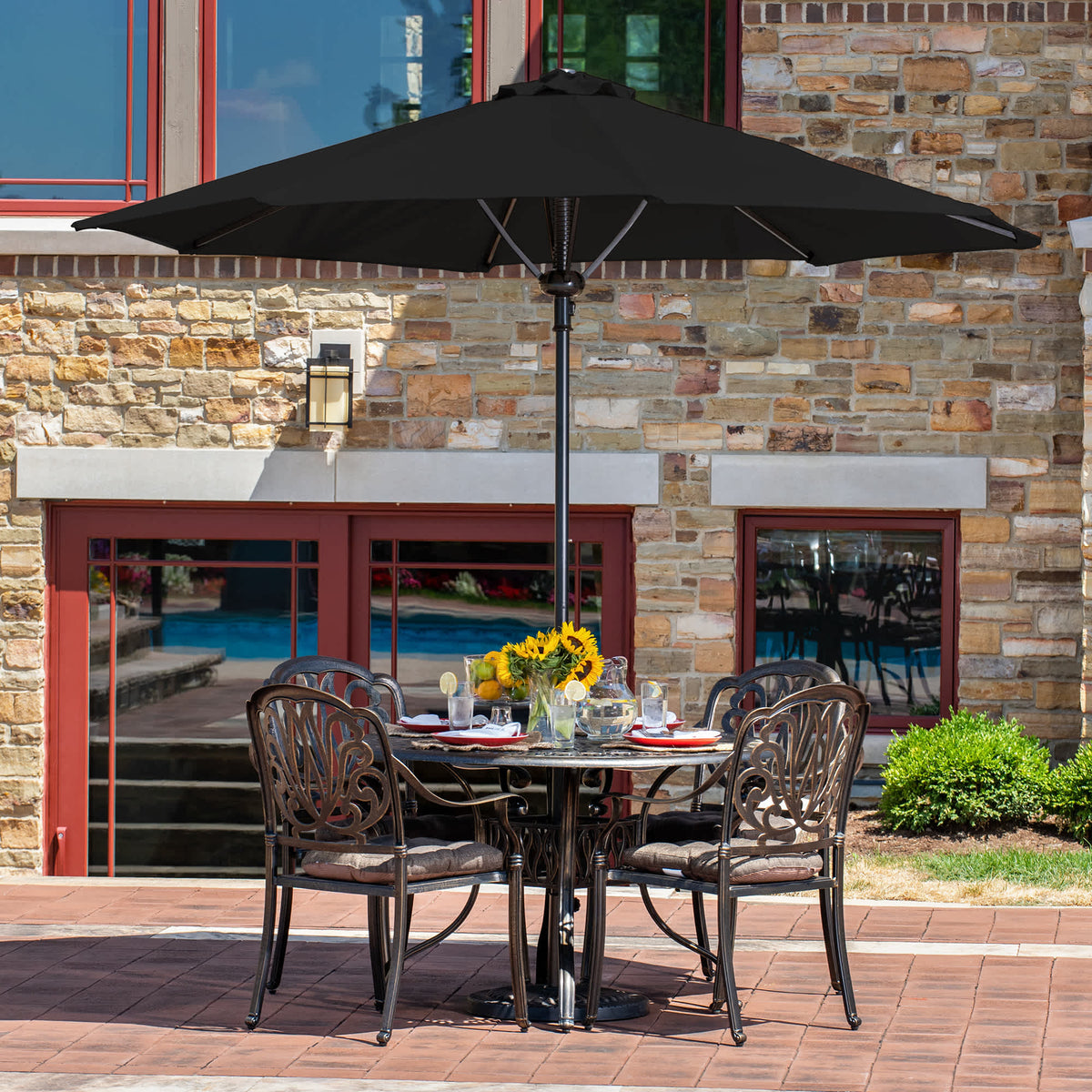 Island Umbrella Cabo Octagonal Umbrella - black canopy over a cast dining set on a brick patio