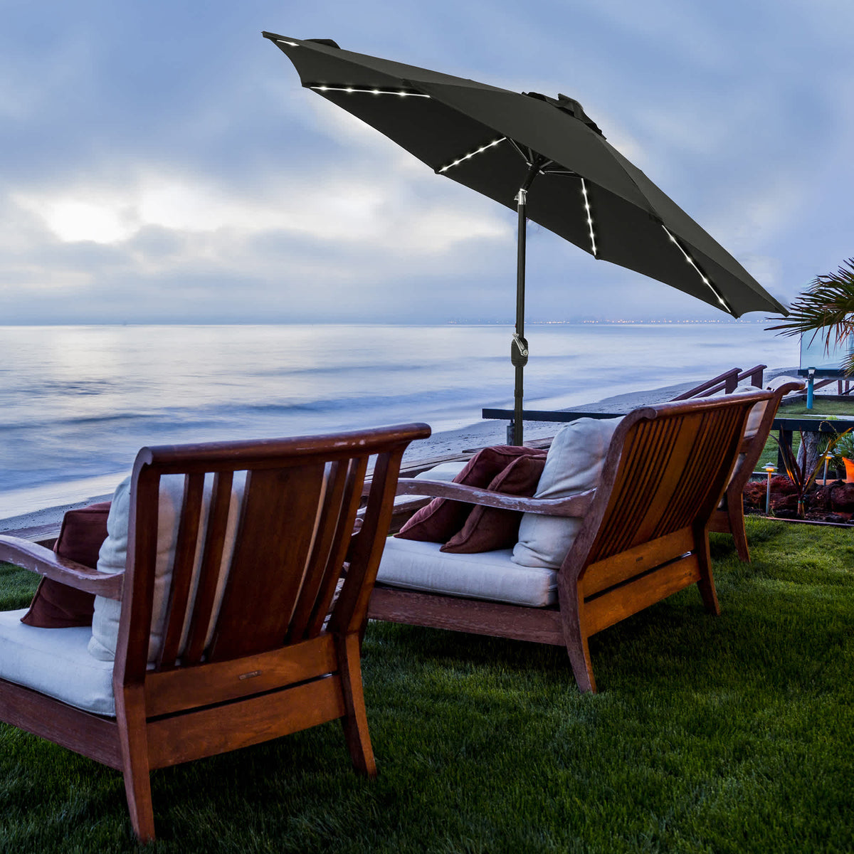 Island Umbrella Mirage Fiesta Umbrella - LED tube lights lit over seating at dusk by the sea