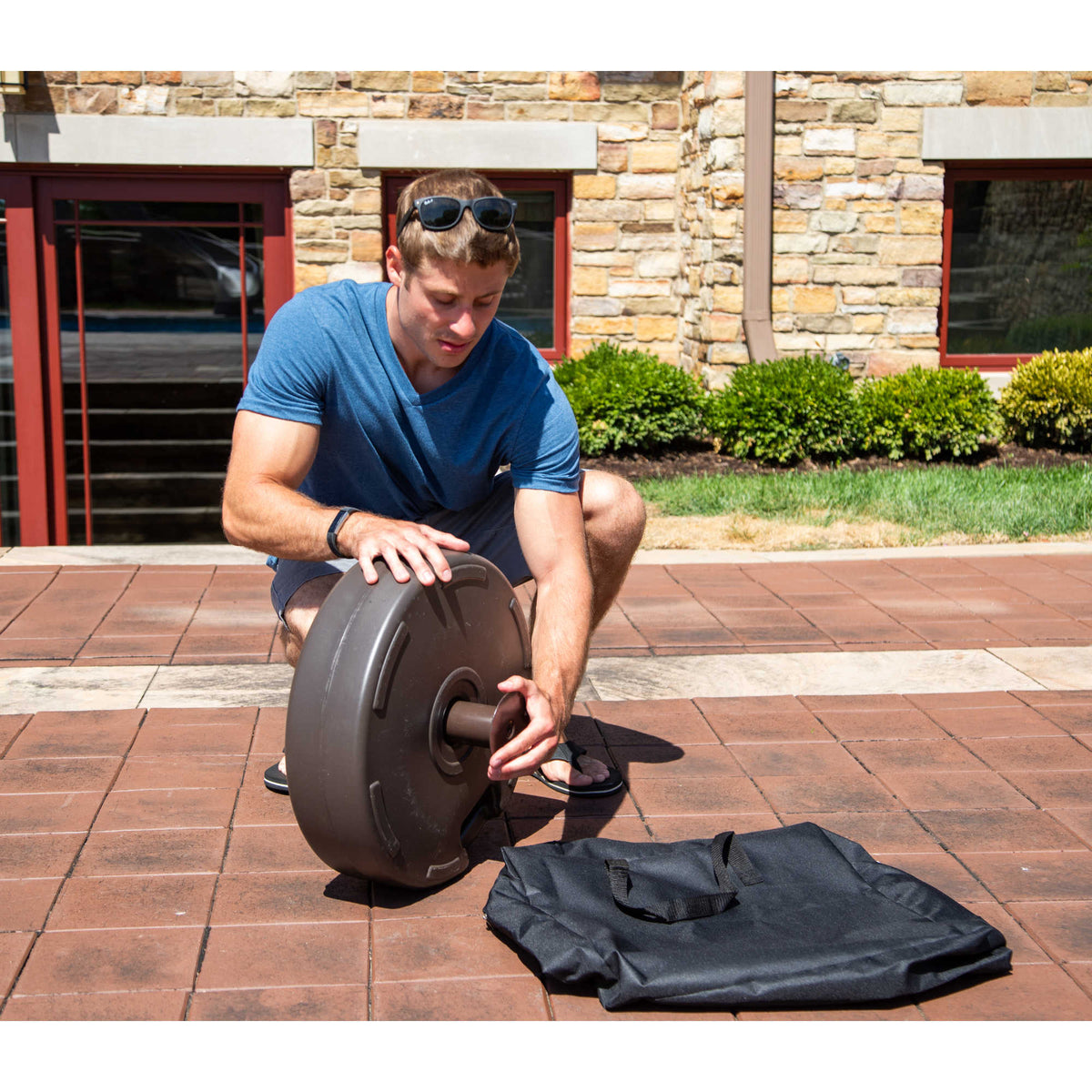 Island Umbrella Fillable Base - base tipped on edge during assembly with its cover bag alongside