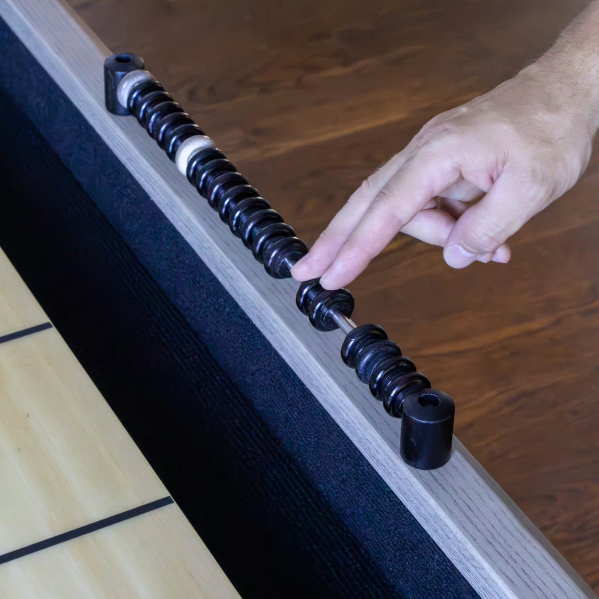 Hathaway Montecito Shuffleboard - hand sliding a bead along the wooden abacus scorer