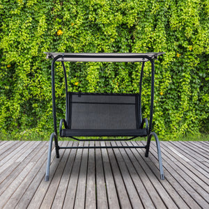 Island Retreat Sea Breeze Dual Swing - two-seat swing with canopy on a deck against a hedge